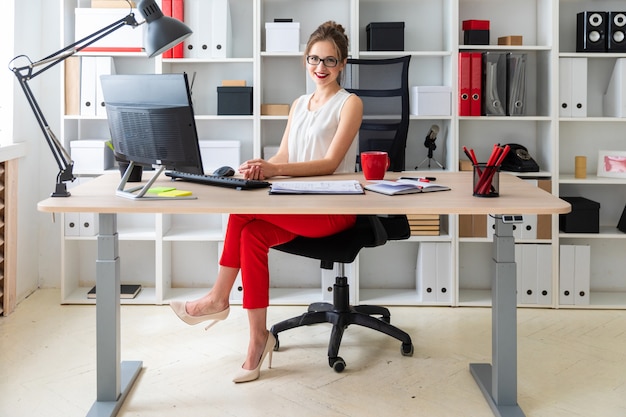 A young girl is sitting at the desk in the office.