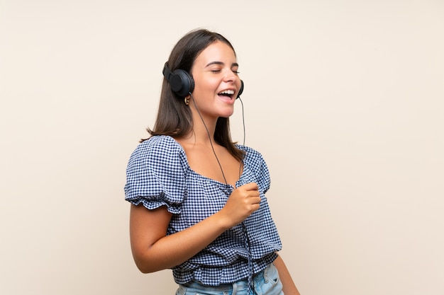 Young girl over isolated wall listening to music with headphones