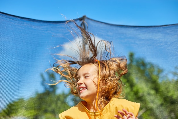 Photo a young girl jumping up down on her trampoline outdoors, in the backyard  house  sunny summer day