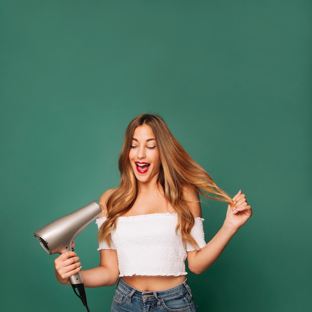 Young girl laughing with hairdryer