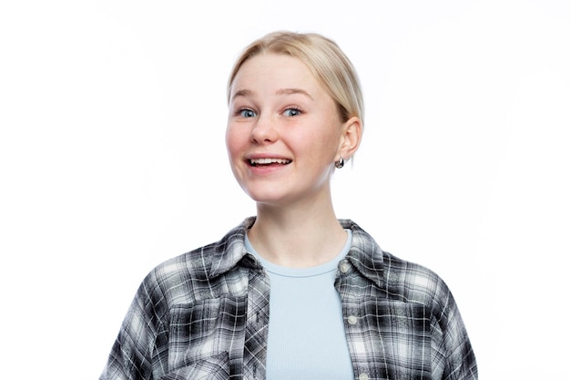 The young girl laughs A cute blonde with freckles on her face wearing a black and white checkered shirt and a blue top Positivity optimism and charm Isolated on a white background Closeup