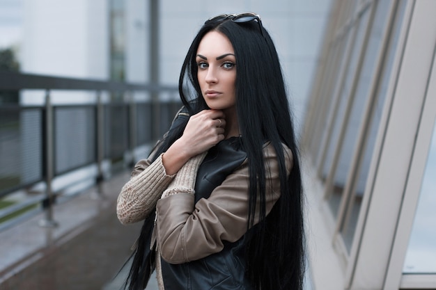 young Girl in a leather jacket standing near a building