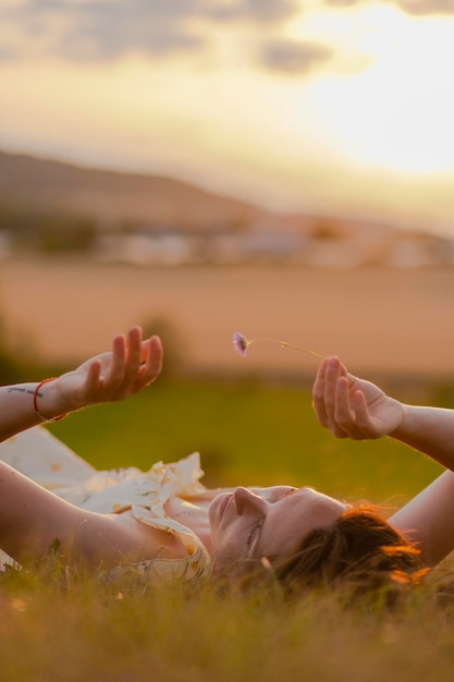 A young girl lies in the grass on the field in the rays of sunset Beautiful girl posing in a field at sunset Vertical photo