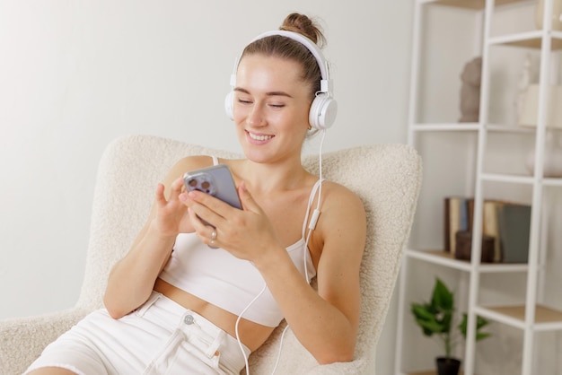 Young girl listens to music in headphones with phone at home concept of free time vacation