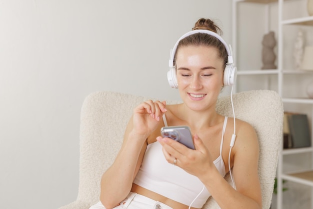 Young girl listens to music in headphones with phone at home concept of free time vacation