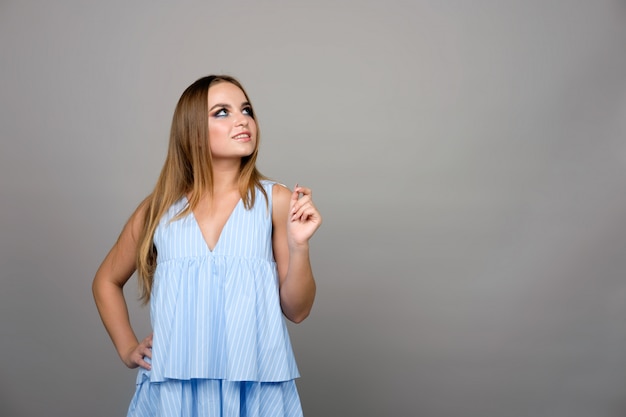 Young girl looking up in thinking manner isolated on gray, copy space