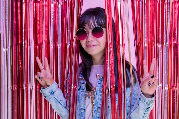 Young girl making peace and love sign wearing glasses at a party