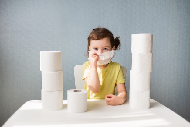 A young girl in a mask is sitting at a table