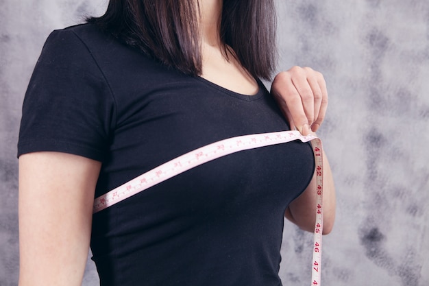 Young girl measures her breasts with a tape