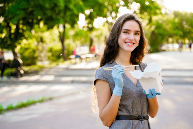 Young girl in medical gloves holds wok in box