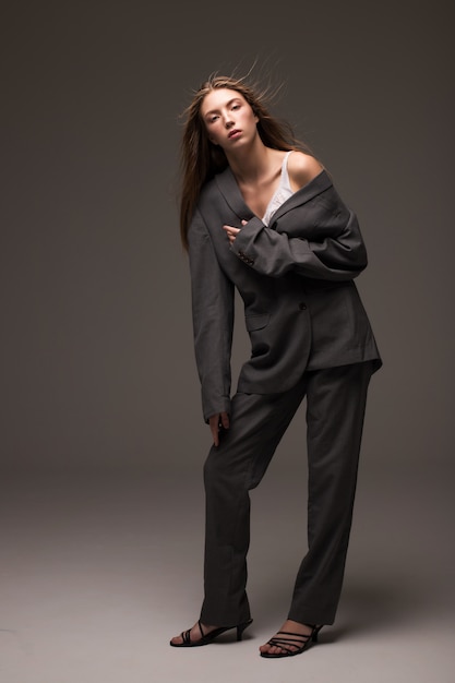 Photo young girl model in grey man suit standing in studio