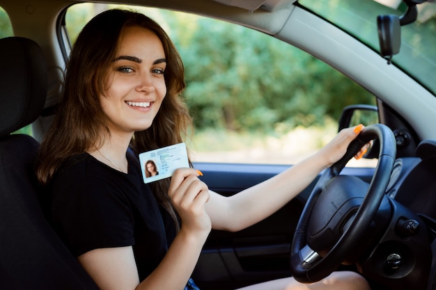 Young girl in a modern car showing driving licence