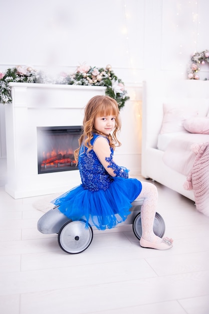 Young girl near the Christmas tree with gifts festively dressed