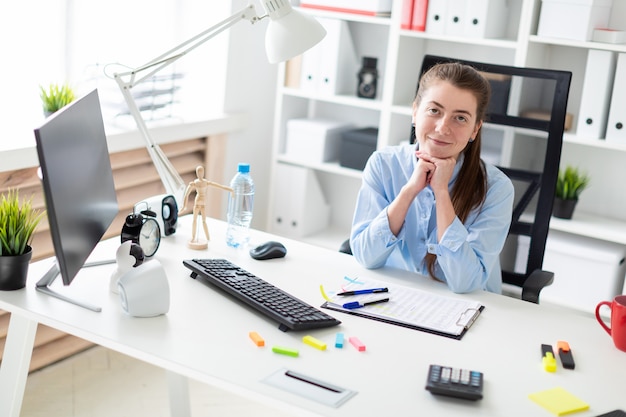 Young girl in the office sits at the computer desk.