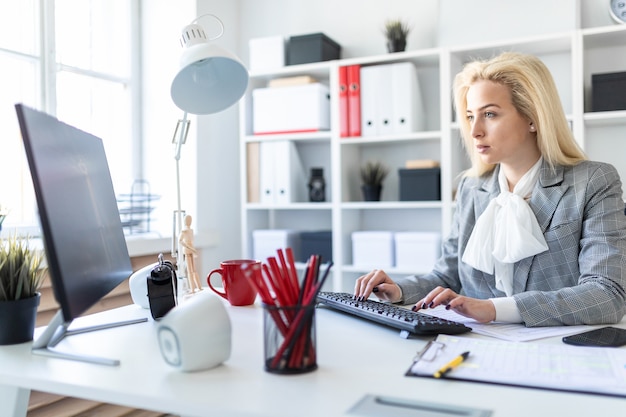 Young girl in office working with computer and documents.