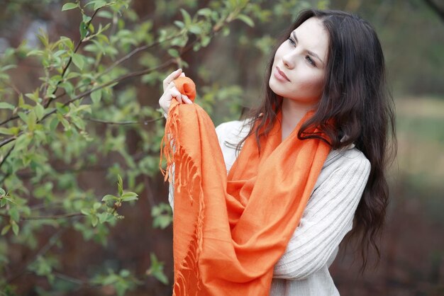 young girl in an orange scarf on a walk in the park