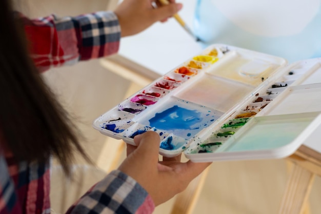 Young girl painting on paper at home wood frameHobby and art study at home