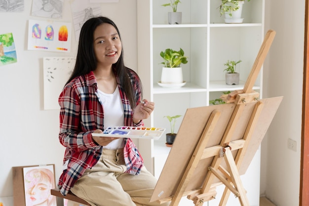 Young girl painting on paper at home wood frameHobby and art study at home