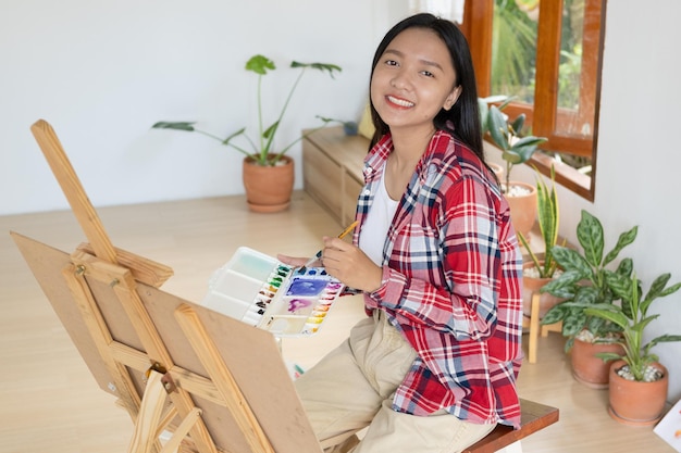 Young girl painting on paper at home wood frameHobby and art study at home