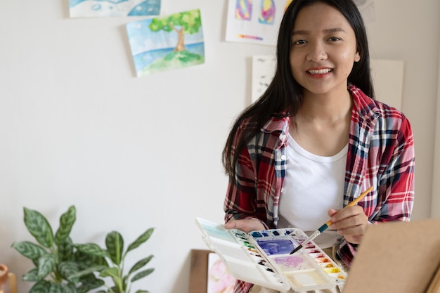 Young girl painting on paper at home wood frameHobby and art study at home