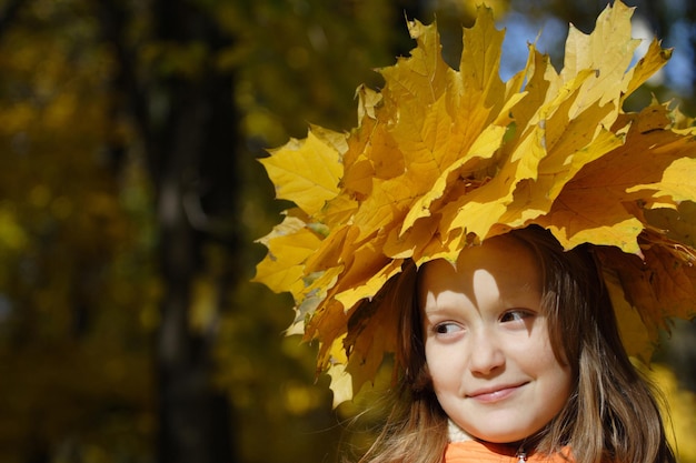 Young girl at the park with diadem from yellow maple leaves