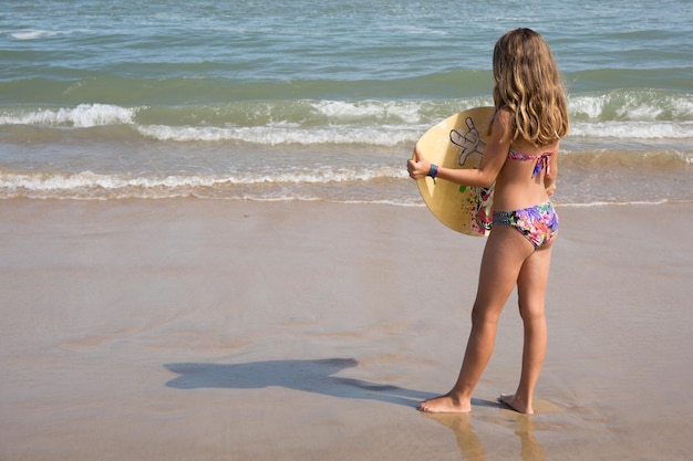 young girl playing beach sea body board