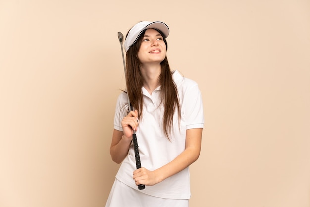 Young girl playing golf and looking up while smiling