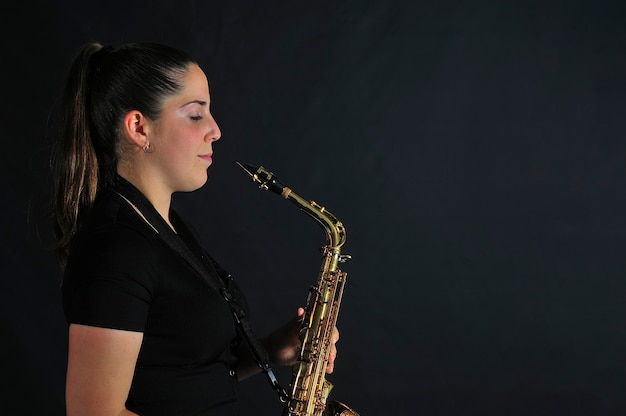 Young girl plays jazz music on saxophone