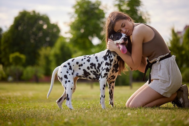 Photo a young girl plays with a dalmatian in the park dog care concept