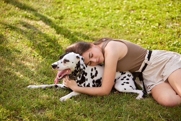 Photo a young girl plays with a dalmatian in the park dog care concept