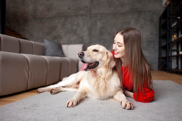 Young girl plays with dog breed golden retriever at home on floor woman with pet together lies