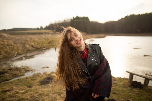 A young girl poses on the shore of a lake