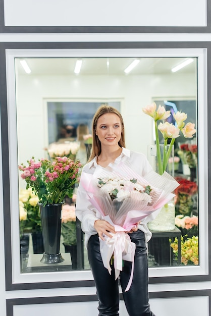 A young girl poses with a beautiful festive bouquet against the background of a cozy flower shop Floristry and bouquet making in a flower shop Small business