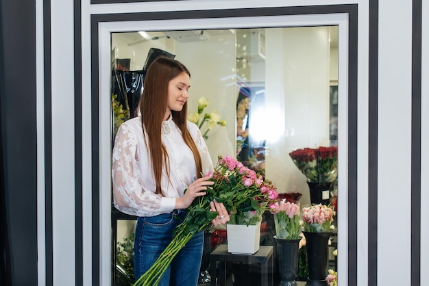 A young girl poses with a beautiful festive bouquet against the background of a cozy flower shop Floristry and bouquet making in a flower shop Small business