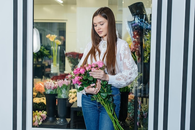 A young girl poses with a beautiful festive bouquet against the background of a cozy flower shop Floristry and bouquet making in a flower shop Small business