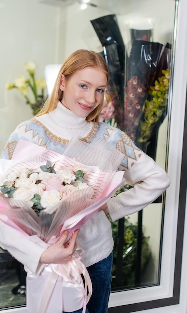 A young girl poses with a beautiful festive bouquet against the background of a cozy flower shop Floristry and bouquet making in a flower shop Small business