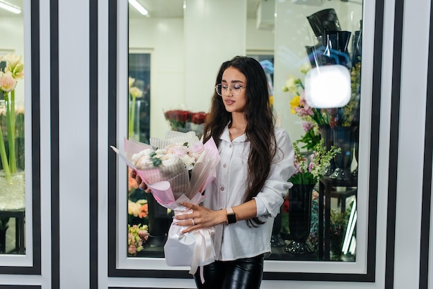 A young girl poses with a beautiful festive bouquet against the background of a cozy flower shop Floristry and bouquet making in a flower shop Small business