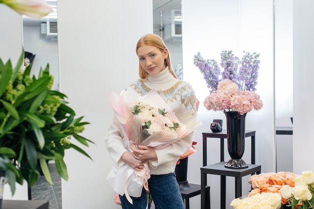 A young girl poses with a beautiful festive bouquet against the background of a cozy flower shop Floristry and bouquet making in a flower shop Small business