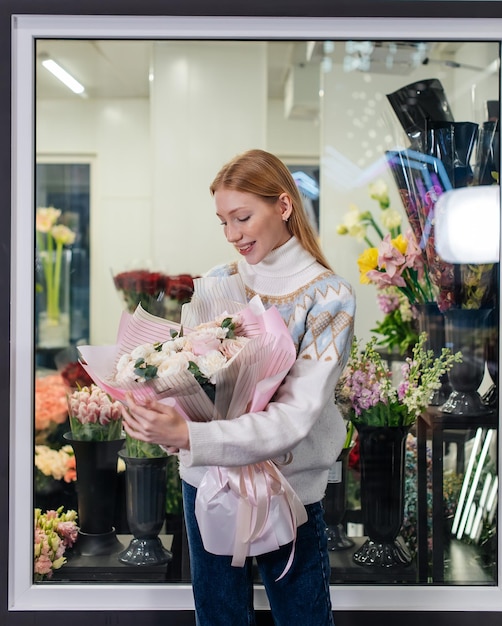 A young girl poses with a beautiful festive bouquet against the background of a cozy flower shop Floristry and bouquet making in a flower shop Small business