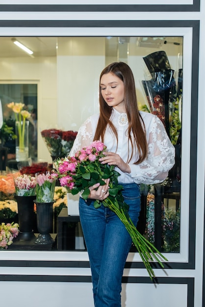 A young girl poses with a beautiful festive bouquet against the background of a cozy flower shop Floristry and bouquet making in a flower shop Small business