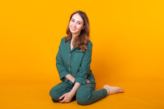 Photo young girl posing in pajamas on yellow wall. relax good mood, lifestyle and sleepwear concept.