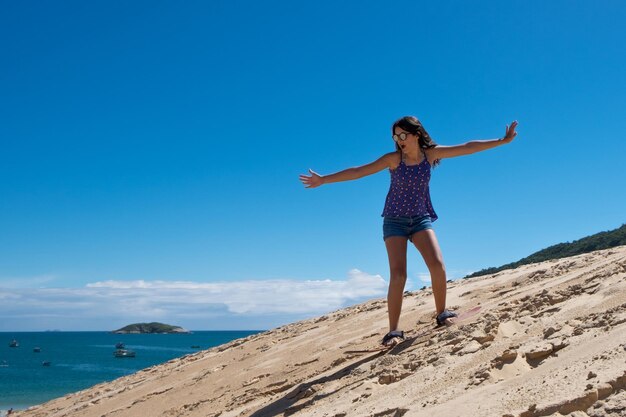 Young girl practicing sandbord in the dunes of Florianopolis, Brazil