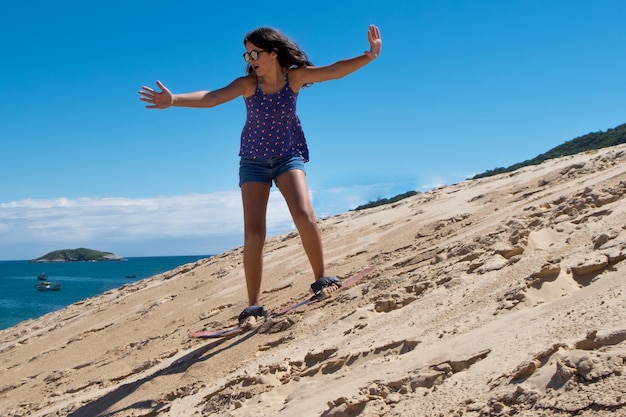 Young girl practicing sandbord in the dunes of Florianopolis, Brazil