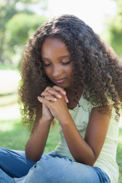 Young girl praying in the park