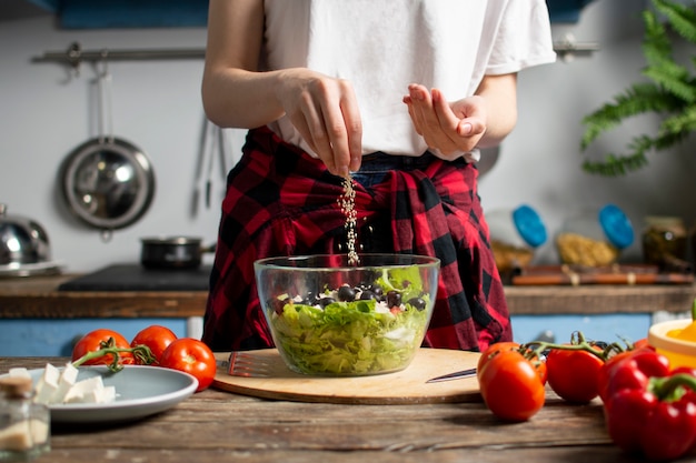 Young girl prepares a vegetarian salad in the kitchen