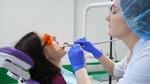 Young girl on preventive examination in dental chair at the dentist. Hands of a dentist with dental tools are checking patient's teeth. Teeth care concept.