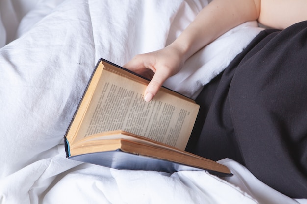 Young girl reading a book in bed