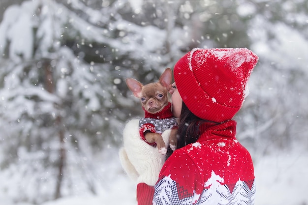 a young girl in a red hat walks on a winter day with a dog, snowfall