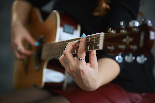 young girl in a red leather miniskirt and black pantyhose playing the guitar