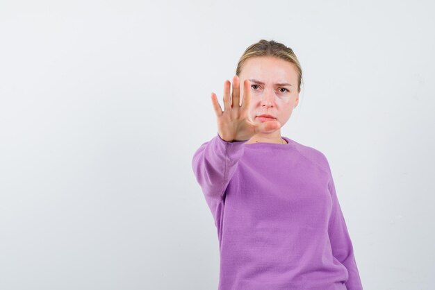 Young girl showing a stop hand sign on white background